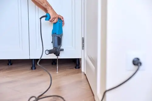 Technician working at a cabinet base during an interior repair